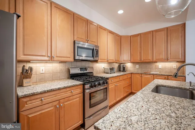 a kitchen with granite countertop a sink stainless steel appliances and cabinets