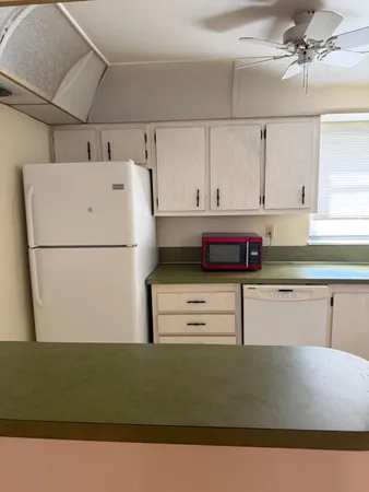 a kitchen with a refrigerator and white cabinets