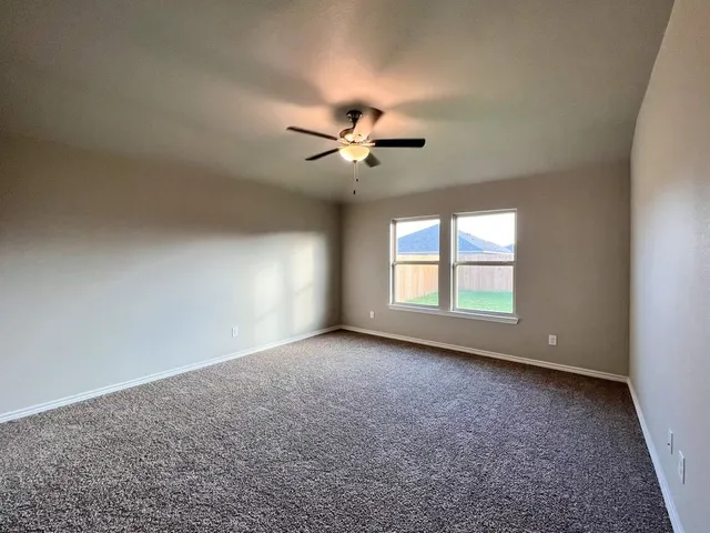 an empty room with a window and a ceiling fan