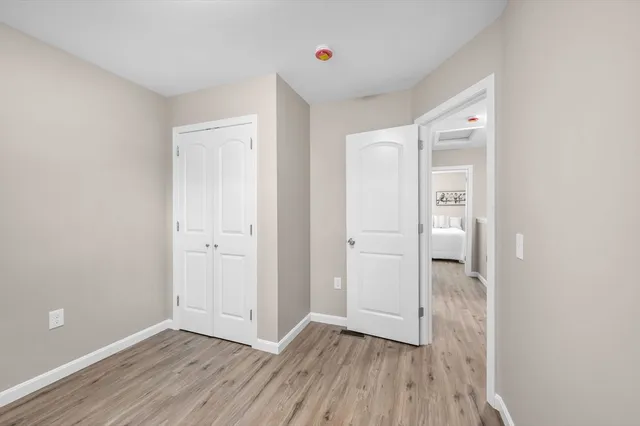 a view of an empty room with closet and wooden floor