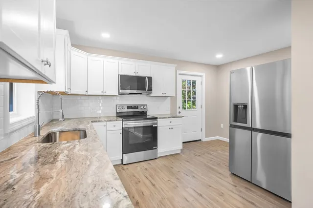 a kitchen with granite countertop a refrigerator stove and microwave