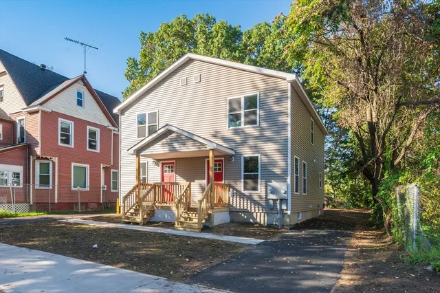 a view of a white house with large windows and a small yard