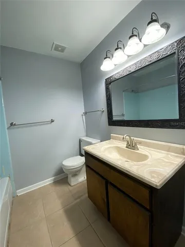a bathroom with a granite countertop sink a toilet and a mirror