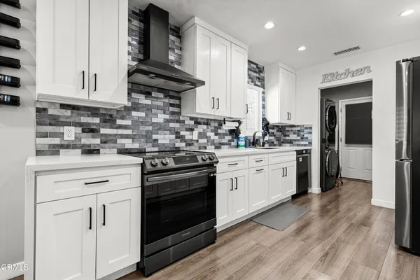 a kitchen with white cabinets stainless steel appliances and wooden floor