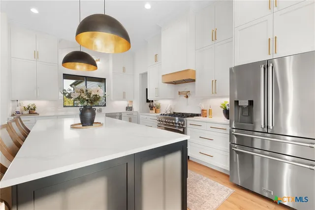 a kitchen with stainless steel appliances granite countertop a sink a stove and a refrigerator