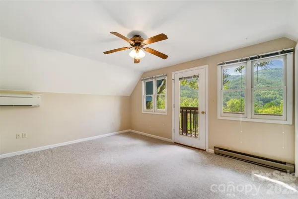 a view of an empty room with window and chandelier fan