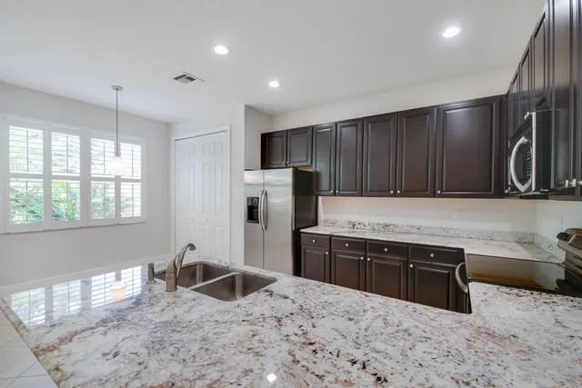 a kitchen with granite countertop a stove refrigerator and microwave