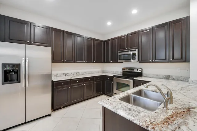 a kitchen with granite countertop wooden cabinets a refrigerator and a sink