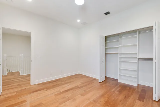 a view of an empty room with wooden floor and closet