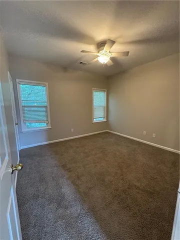 an empty room with windows and fan