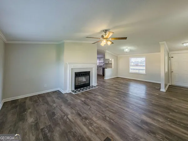 an empty room with windows fireplace and wooden floor