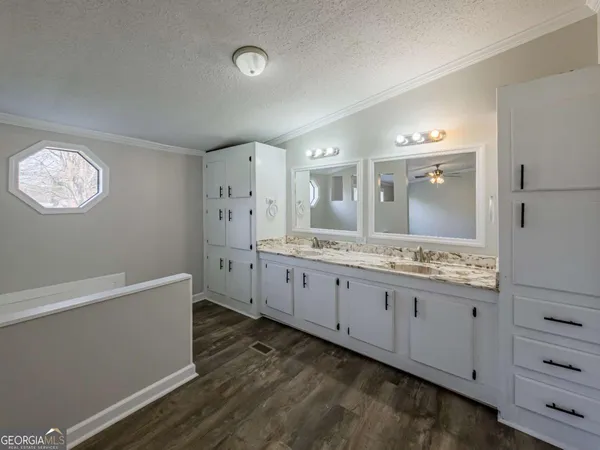 a spacious bathroom with a granite countertop sink a mirror and a bathtub