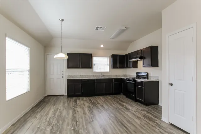 a large kitchen with stainless steel appliances granite countertop a stove and a wooden floors