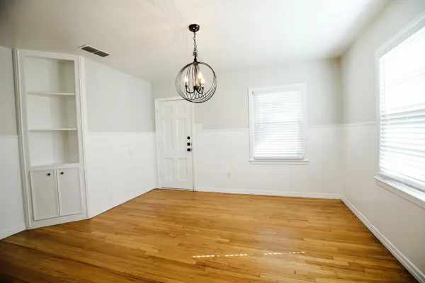 a view of empty room with wooden floor and window