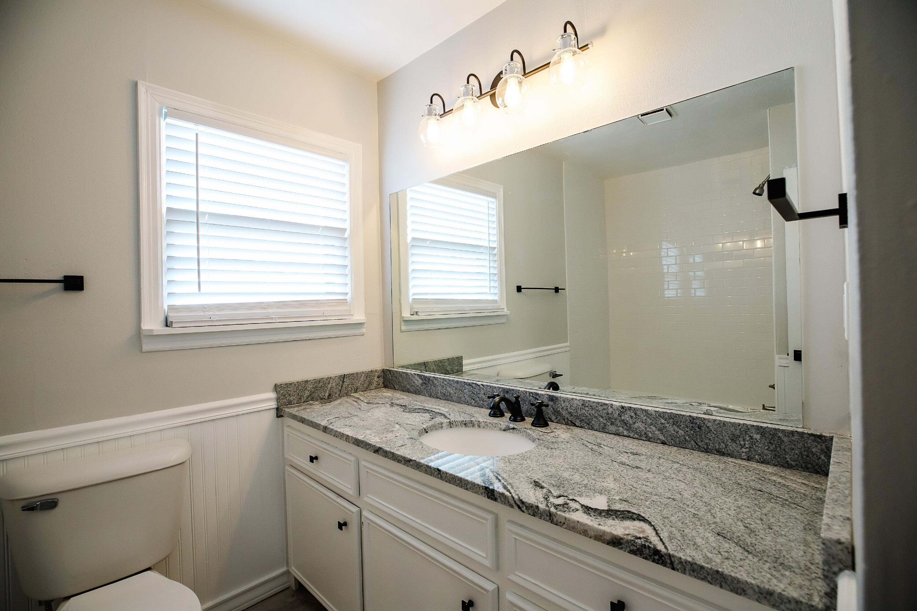3409 29th Street Lubbock, TX 79410 - Photo 5 of 16 a bathroom with a granite countertop sink and a mirror