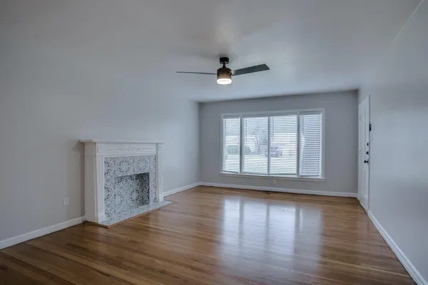 an empty room with wooden floor fireplace and windows