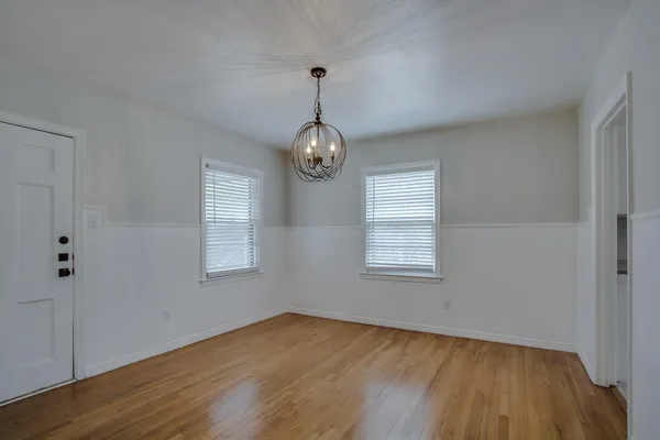 a view of an empty room with wooden floor and window
