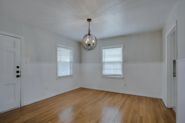 a view of an empty room with wooden floor and window