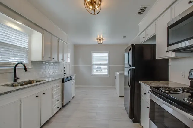 a kitchen with stainless steel appliances granite countertop a refrigerator stove and sink