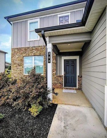 a view of a house with potted plants and a table and chairs
