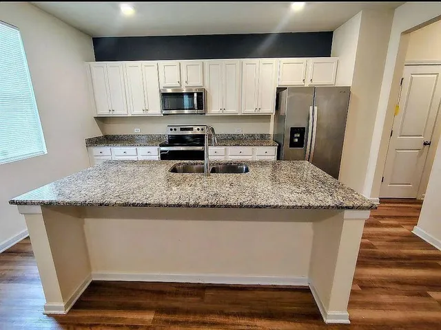 a kitchen with stainless steel appliances granite countertop a refrigerator a stove and a sink