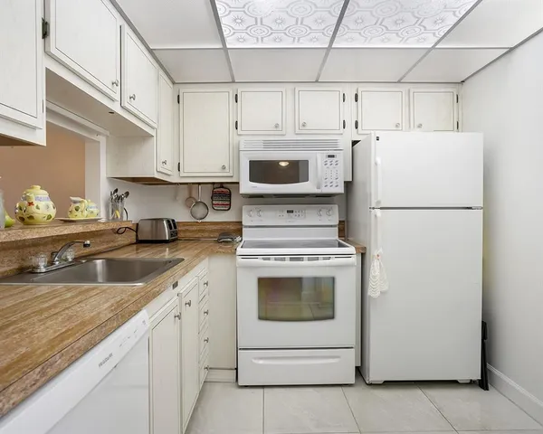a kitchen with cabinets a sink and white appliances