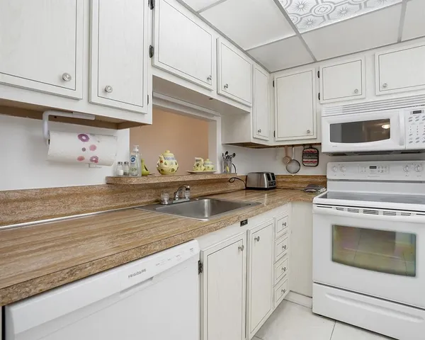 a kitchen with granite countertop white cabinets white stainless steel appliances and a sink