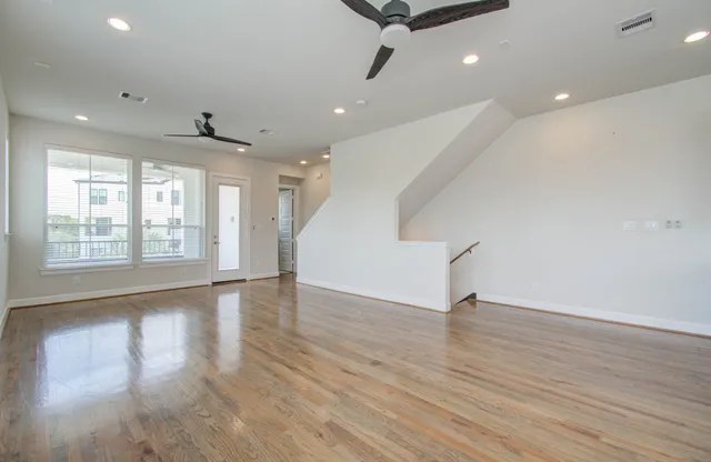 a view of an empty room with wooden floor and a window