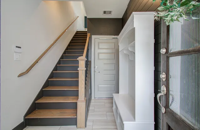 a view of staircase with lots of frames on wall and a potted plant