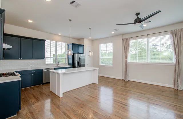 a kitchen with granite countertop a stove top oven a sink a counter space and wooden floor