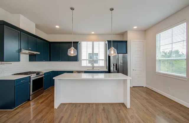 a large kitchen with stainless steel appliances granite countertop a stove and a wooden floors