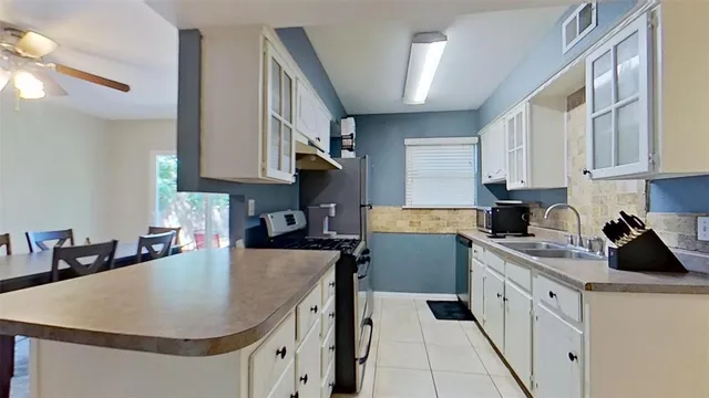 a kitchen with kitchen island granite countertop a sink a stove and cabinets