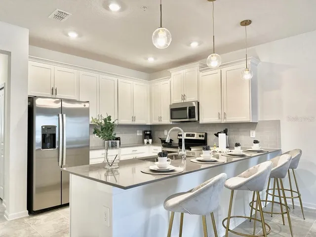 a kitchen with stainless steel appliances kitchen island granite countertop a sink a stove a refrigerator and island with wooden floor