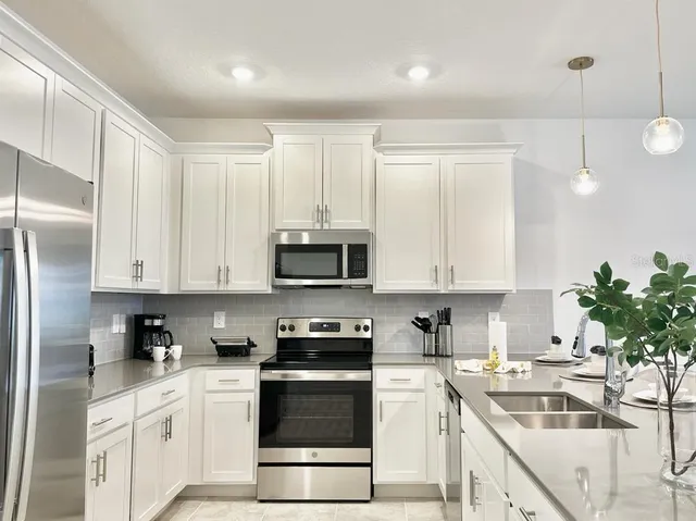 a kitchen with stainless steel appliances granite countertop a refrigerator sink and white cabinets