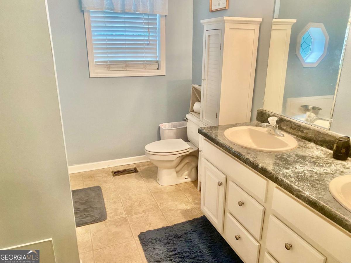 290 Poplar Creek Road Stephens, GA 30667 - Photo 46 of 68 a bathroom with a granite countertop sink a toilet and a mirror