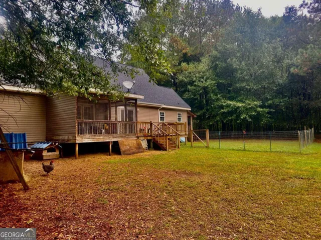 a view of swimming pool with lawn chairs and large trees