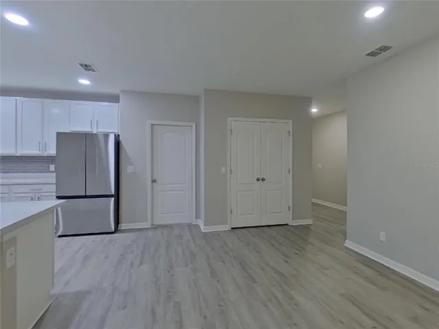 a view of a kitchen with a refrigerator and wooden floor
