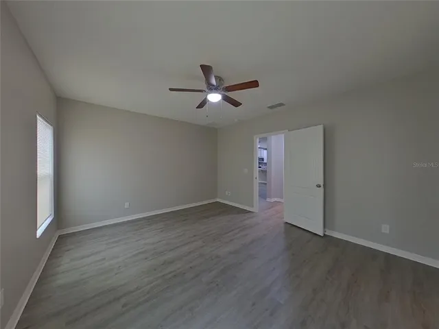 an empty room with wooden floor and ceiling fan