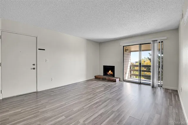 an empty room with wooden floor fireplace and windows