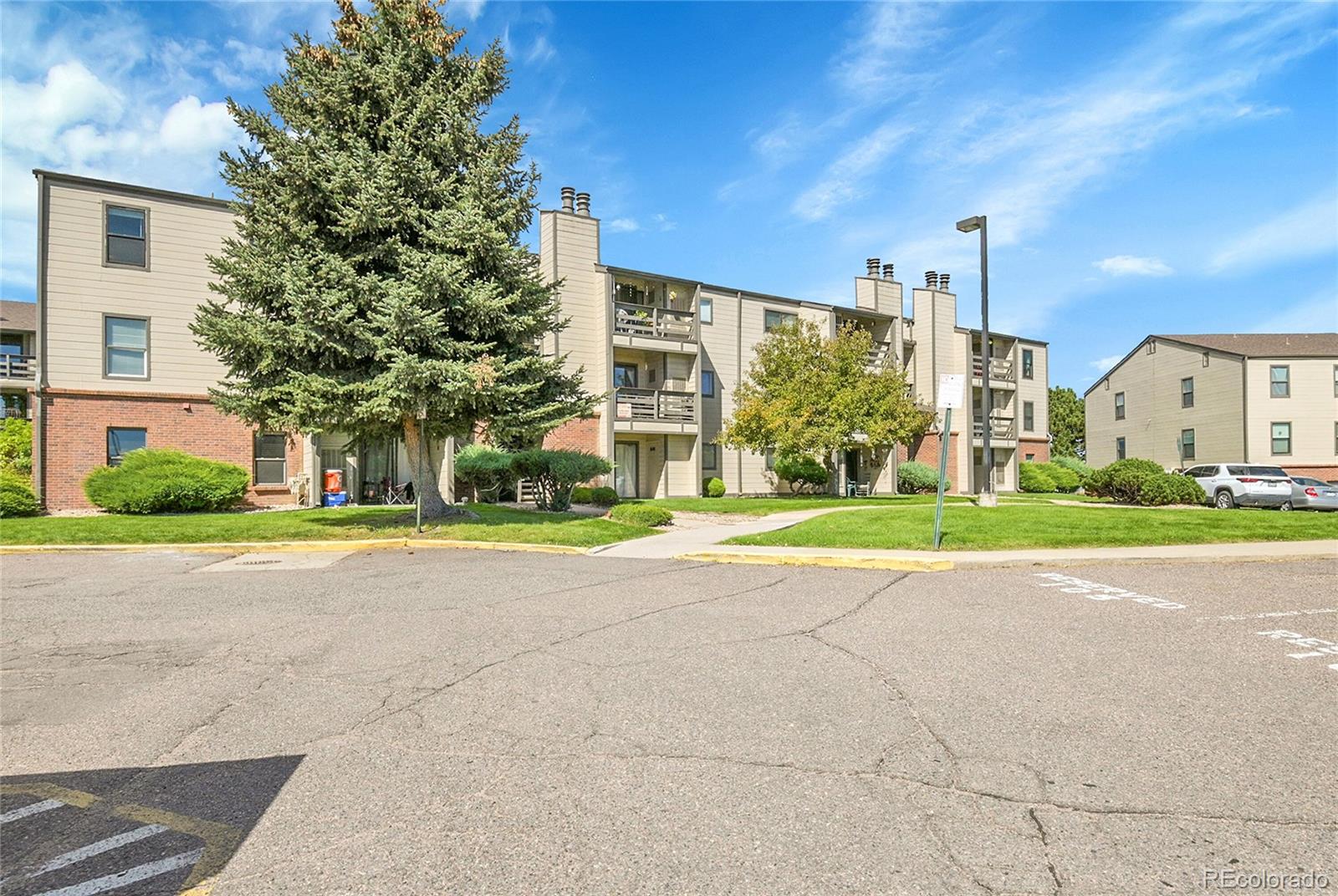539 Wright Street, Unit 301 Lakewood, CO 80228 - Photo 3 of 32 a view of a house with a big yard and large trees