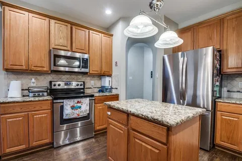 a kitchen with stainless steel appliances granite countertop a stove refrigerator and microwave