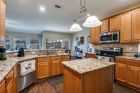 a kitchen with stainless steel appliances granite countertop a stove a sink dishwasher and a microwave oven with white cabinets