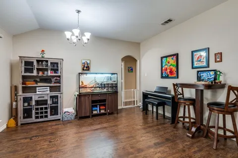 a view of a livingroom with furniture a chandelier wooden floor and a window