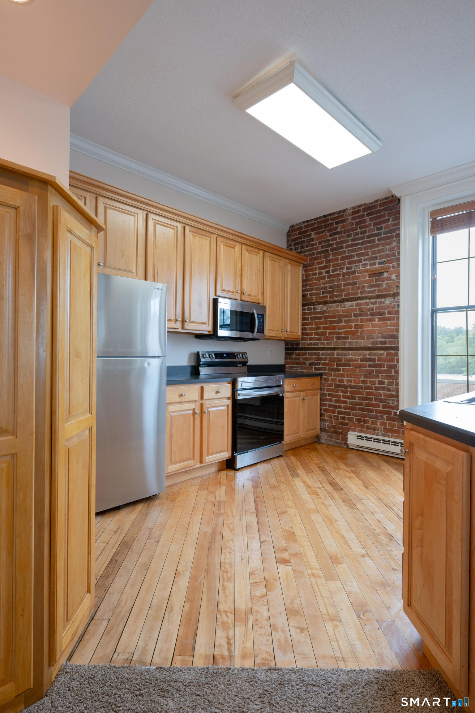 130 Main Street, Unit 2D Canton, CT 06019 - Photo 8 of 25 a kitchen with granite countertop wooden floors stainless steel appliances and a window