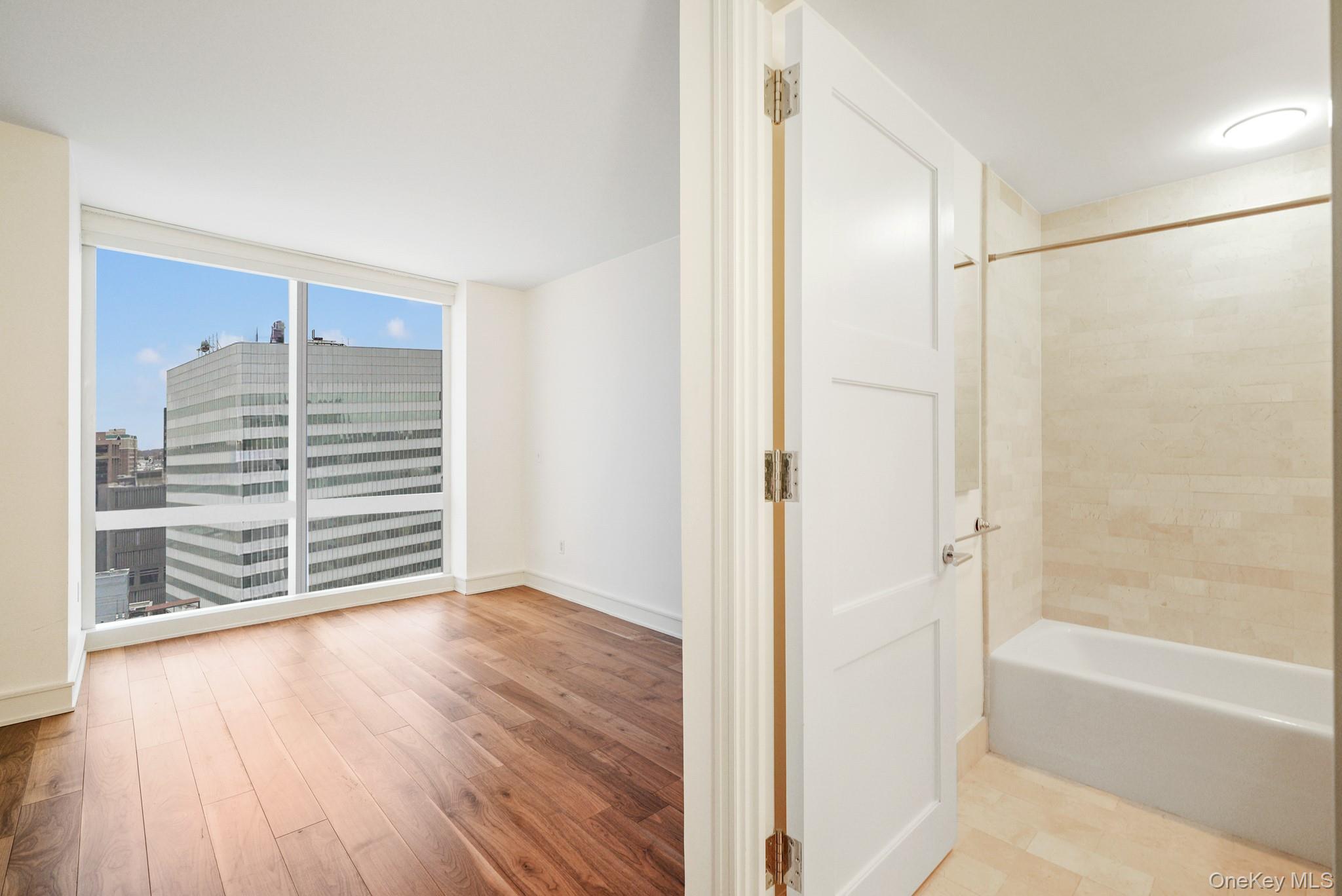 1 Renaissance Square, Unit 15E White Plains, NY 10601 - Photo 18 of 27 a view of an empty room with a window and wooden floor