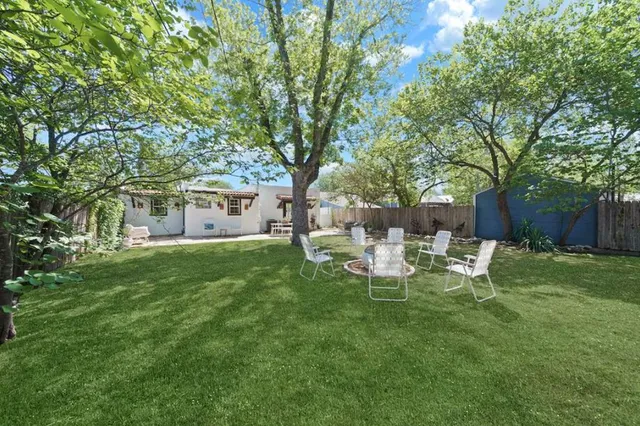 a view of a backyard with table and chairs and a large tree
