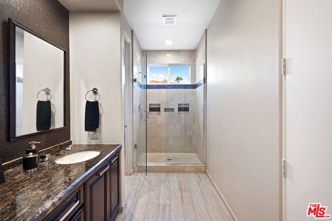 331 Tomahawk Drive Palm Desert, CA 92211 - Photo 30 of 40 a bathroom with a granite countertop sink a mirror and shower