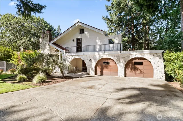 a view of a grey house with large trees