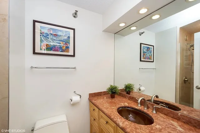 a bathroom with a granite countertop sink a mirror and toilet