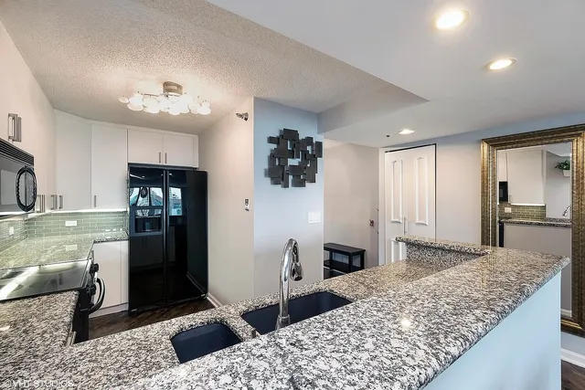 a kitchen with stainless steel appliances kitchen island granite countertop a refrigerator and a sink
